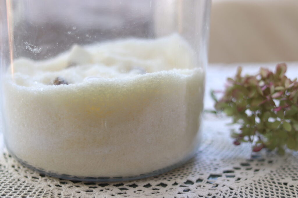 Clear glass jar containing epsom bath salt with essential oils